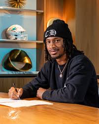 Tutu Atwell Jr. signing at a table