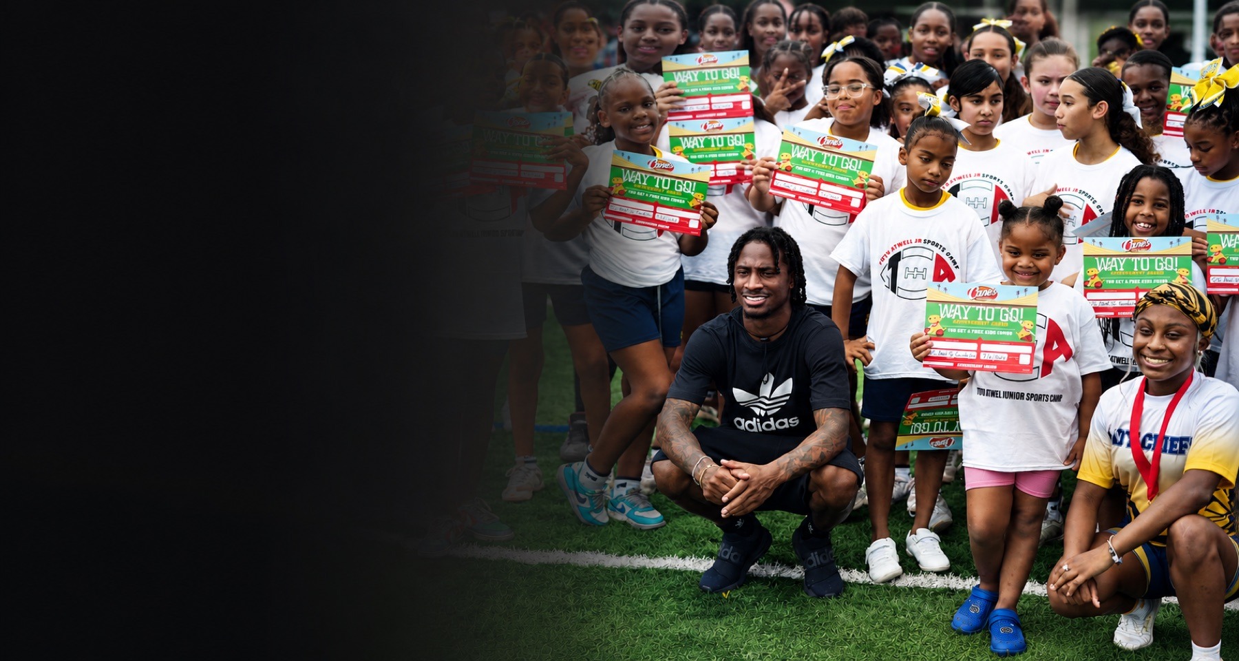 Tutu Atwell Jr. with youth participants celebrating achievement at a foundation sports camp